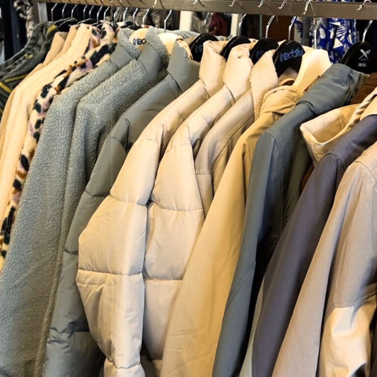 Jacken in Beige- und Grautönen auf einer Kleiderstange